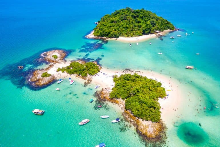 Vista aérea das ilhas paradisíacas e águas cristalinas da Baía da Ribeira em Angra dos Reis, cenário onde a Casa Kaîre está localizada.